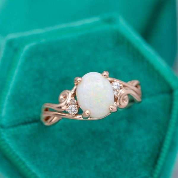 An oval Australian white opal set in a curving rose gold engagement ring.