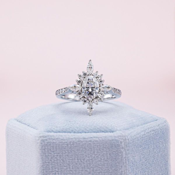 A sunburst halo surrounds the moissanite at the center of this white gold ring.