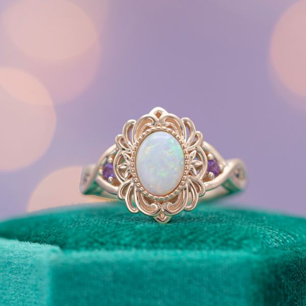 A frame of intricate rose gold wirework creates a faux-halo around this ring's opal center stone.