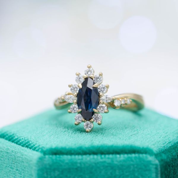 We designed this vintage-inspired engagement ring with a sunburst halo around an inky, midnight blue sapphire.