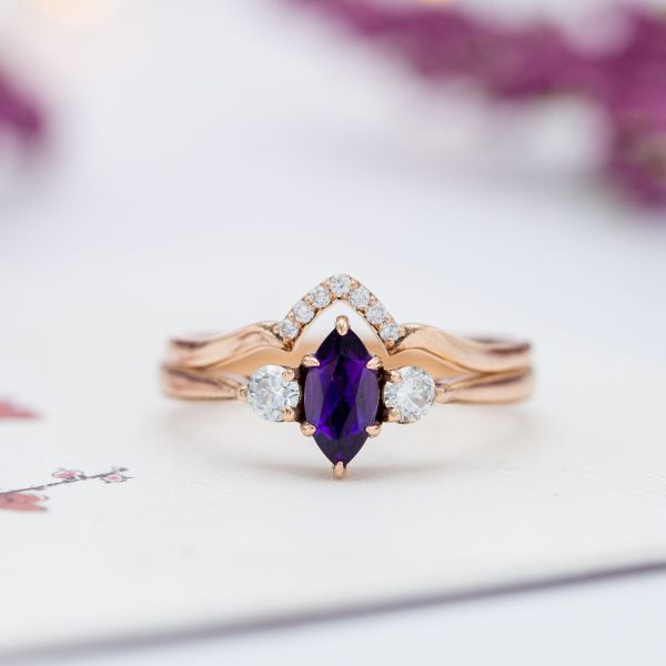 A deep purple amethyst pairs with diamonds in a three stone engagement, and a matching wedding band adds sparkle.