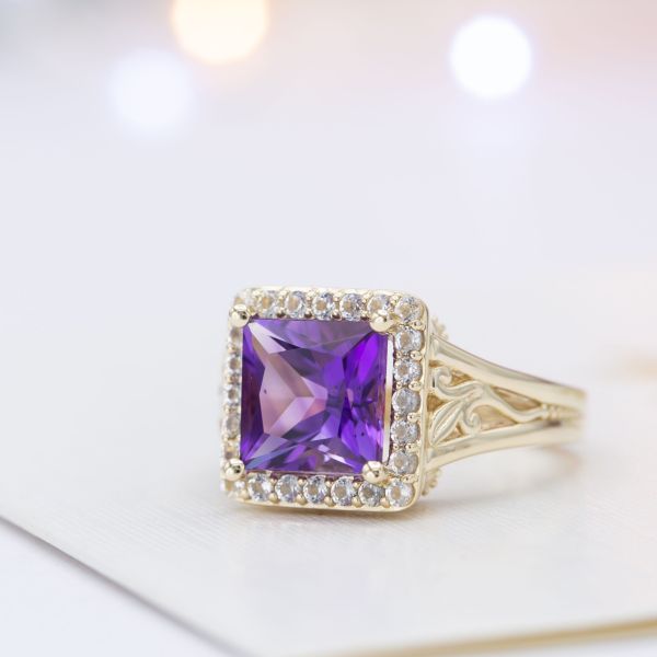 A bold amethyst engagement ring with a princess cut center stone, halo, and vine detailing.