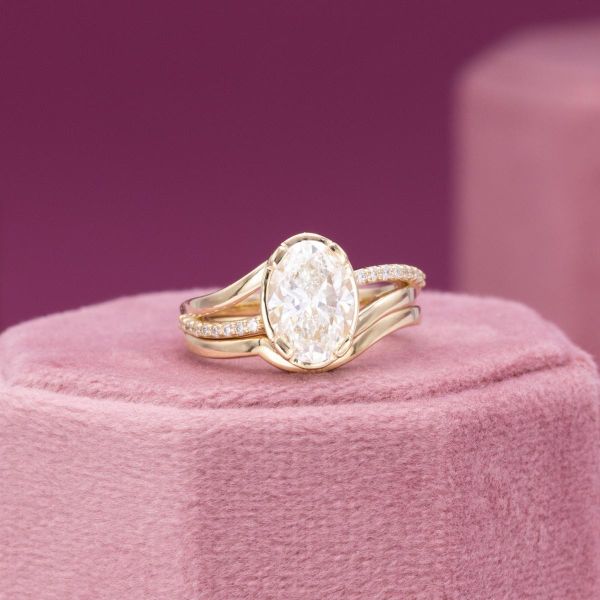 A bright white lab diamond sits in this wavy yellow gold bridal set.