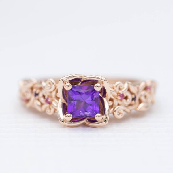 A custom-cut princess amethyst with a touch of red set in a flower-inspired ring with an intricately vining band.