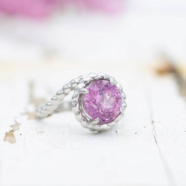 Pink spinel ring with a rope band in a bypass setting.