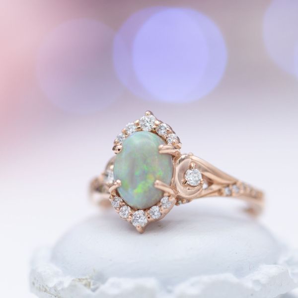 An elegant, vintage-inspired engagement ring featuring the blue-green shimmer of opal as its center stone.