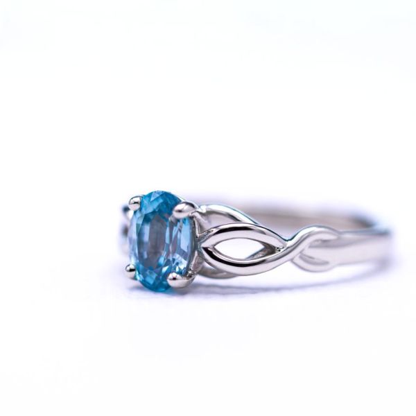 Engagement ring with vining rope detail and oval blue zircon center stone.