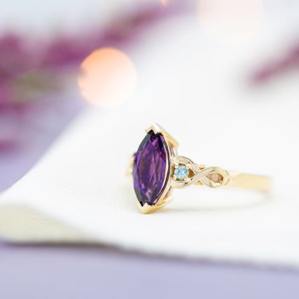 Marquise cut amethyst engagement ring with twisting gold band an diamond accents.