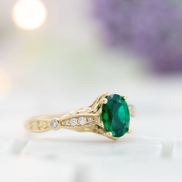 Emerald engagement ring with vintage-style band detailing.