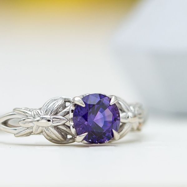 A nature-inspired white gold engagement ring with a royal purple sapphire center stone.