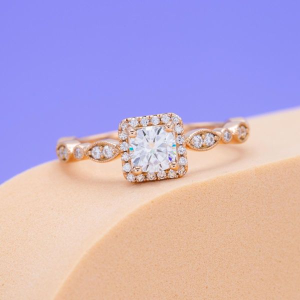 A timeless take on an antique inspired engagement ring with a round moissanite center stone.