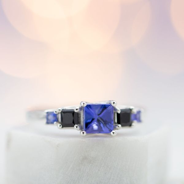 Five stone engagement ring with trellis-set princess cut tanzanite and black spinel.