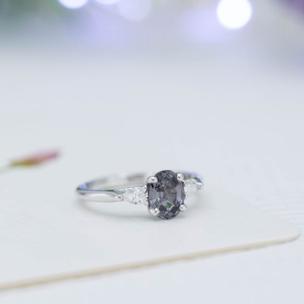 Gray spinel engagement ring with pear cut diamonds in a three-stone setting.