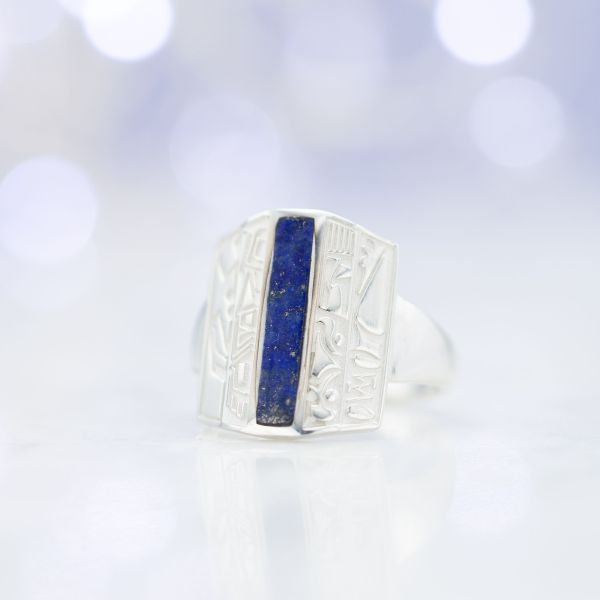 A unique lapis lazuli ring with tribal symbols engraved along the elongated face.