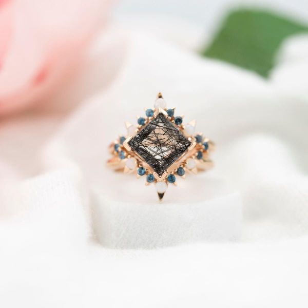 Striking tourmalinated quartz engagement ring with sunburst-style halo of topaz and opals.
