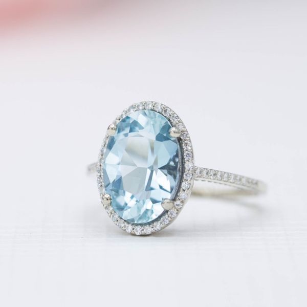 A big, bright aquamarine center stone engagement ring with a thin halo of diamonds.