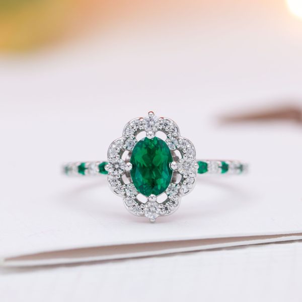 A floating, scalloped halo surrounds the emerald in this engagement ring.