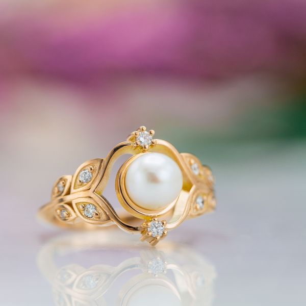 Pearl engagement ring in rose gold with a floral, leafy setting.