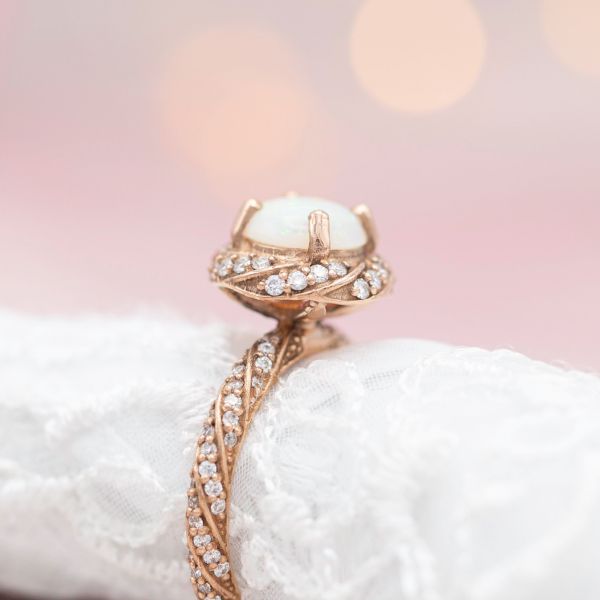 Twisting bands of diamond create a vortex of sparkle along the band and in a halo around this ring's opal center stone.