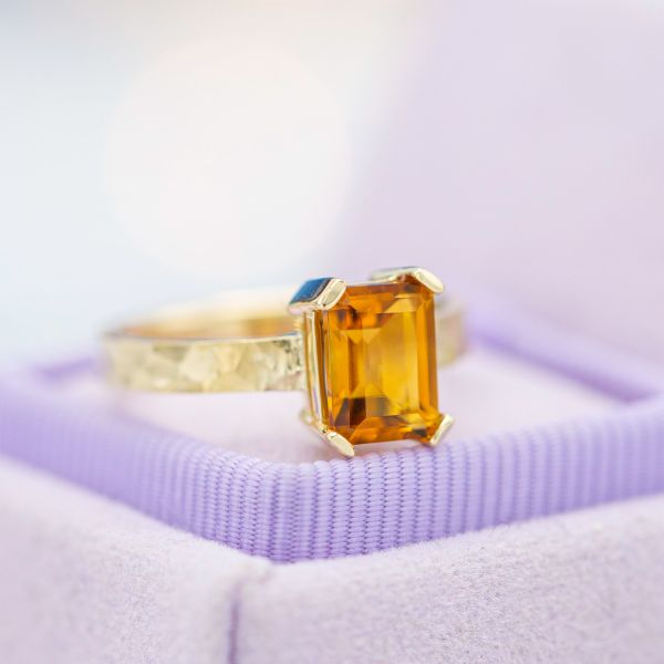 Emerald cut citrine engagement ring with a modern prong setting and hammered band.