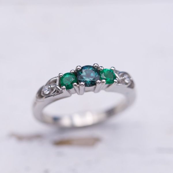 Three stone engagement ring with alexandrite and emeralds and trinity knots.