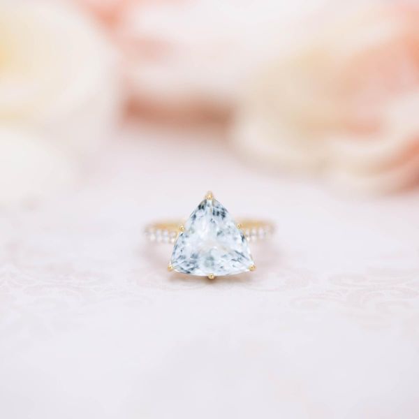 A bright blue, trillion cut aquamarine stars in this gold engagement ring.