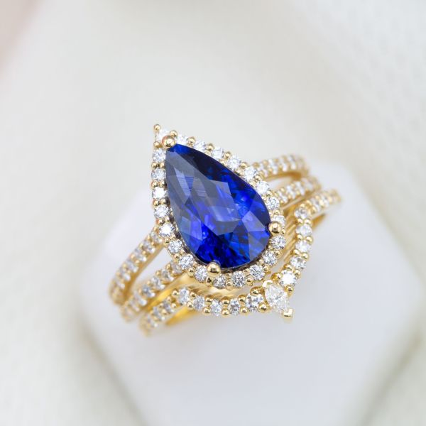 A heat-treated pear sapphire is the perfect blue centerpiece of this sparkly, gold bridal set.