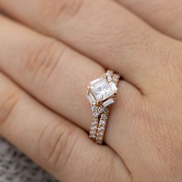 Baguette diamonds trace the outer edges of the kite set princess cut diamond in this modern ring.