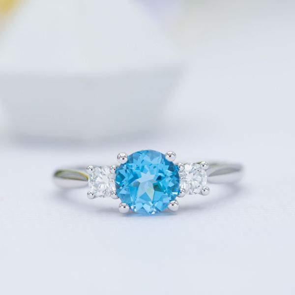 Three-stone engagement ring with Swiss blue topaz and diamonds.