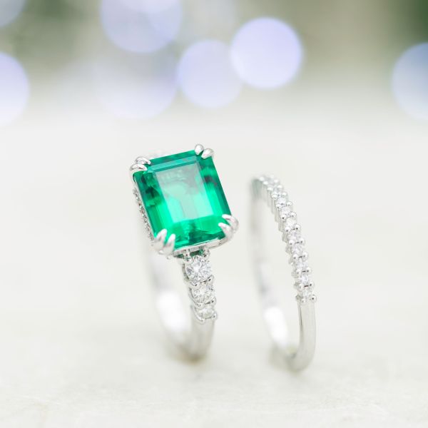 Emerald engagement ring and matching wedding band, with east-west setting for the emerald cut center stone.