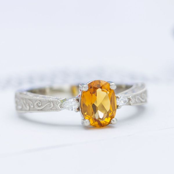 Three stone engagement ring with citrine and diamonds with scrollwork and milgrain on the band.