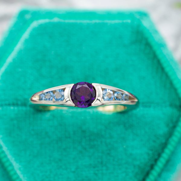 The amethyst center stone in this ring has a semi-bezel setting, with openings on two sides that show off more of the gem.