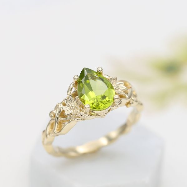 Sculptural, floral ring inspired by a dogwood branch and flowers, with a pear cut peridot center.