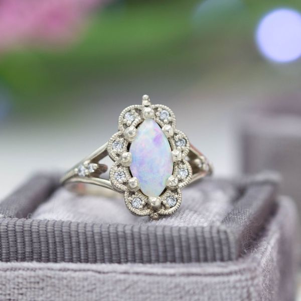 A vintage-inspired marquise cut opal engagement ring with an exaggerated scalloped frame halo.