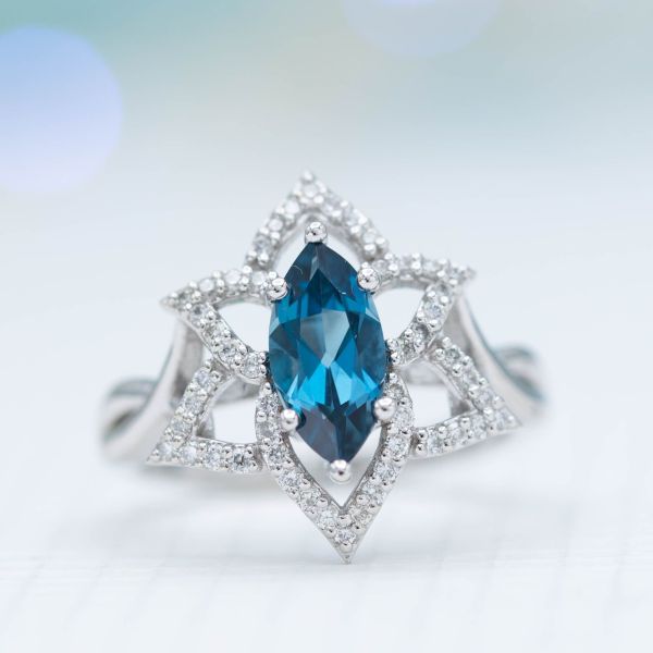 Open, halo-style engagement ring with London blue topaz, inspired by the amaryllis flower.
