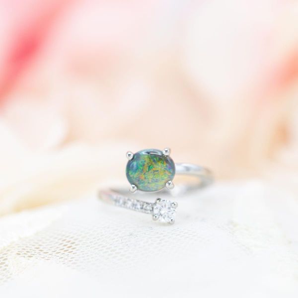 A modern, asymmetrical take on a two-stone engagement ring with black opal and diamond.