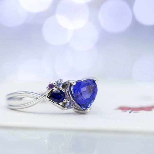 Engagement ring with heart cut tanzanite and asymmetrical clusters of aquamarine, sapphire, and more tanzanite.