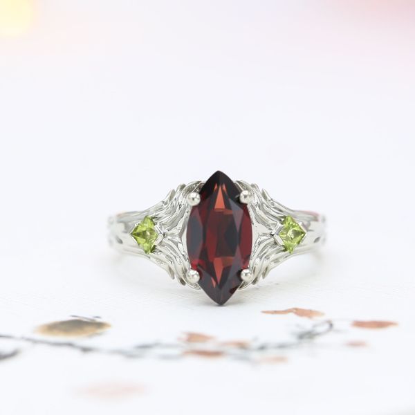Unique setting with marquise Mozambique garnet framed by wings and peridot accents.