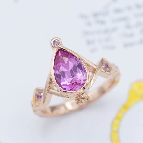 This unique rose gold ring features a vivid, violet-hued pink sapphire in a pear cut.