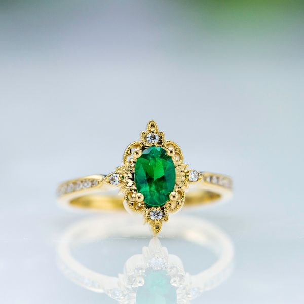 Vintage-inspired emerald engagement ring with an antique halo framing the center stone.