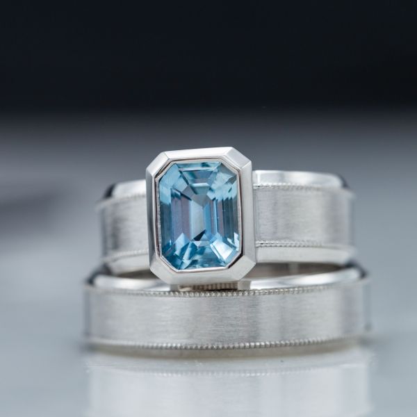 Bold, modern aquamarine engagement ring with a wide band and bezel accenting the gem's geometry.
