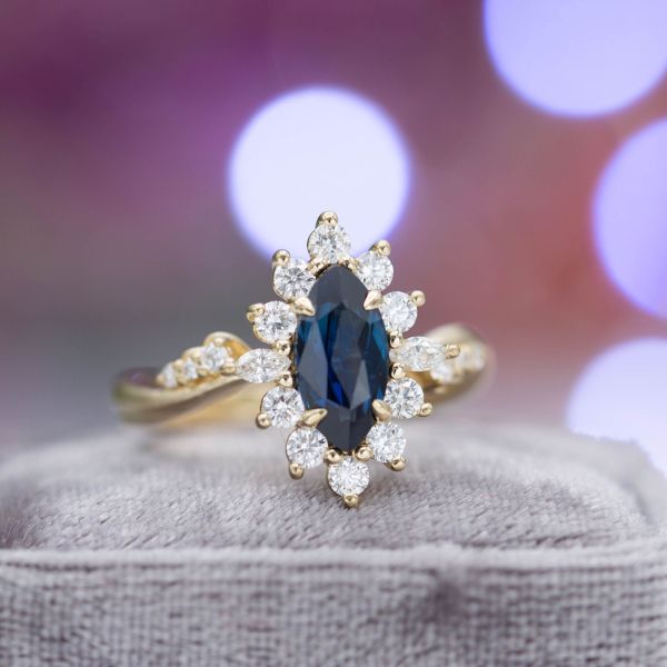 Midnight blue marquise sapphire surrounded by a sunburst halo and curvy, tapered band.