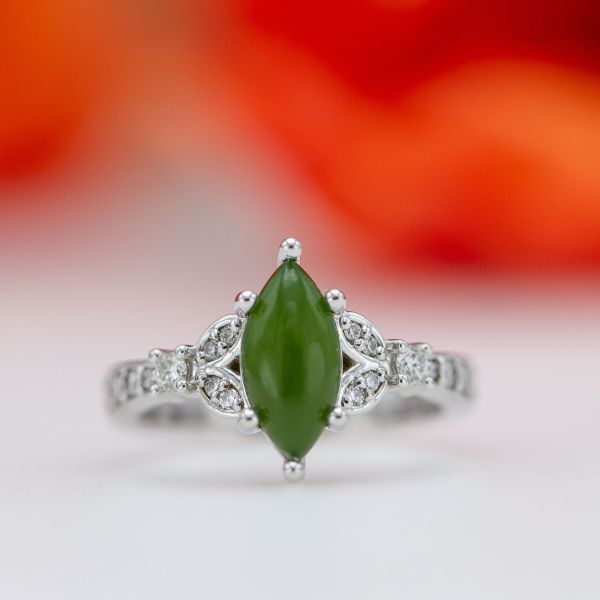 This jade engagement ring echoes the marquise shape of the center stone with the diamond-studded split band around it.