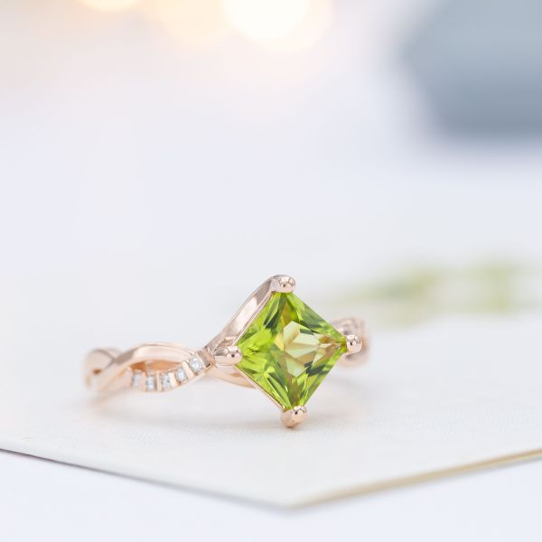 Bypass engagement ring in rose gold with a kite set princess cut peridot center stone.
