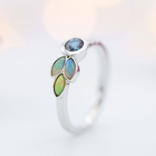 Marquise cut white opals create a pretty asymmetrical accent cluster in this modern alexandrite ring.