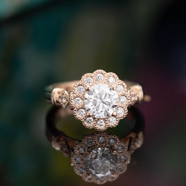 Using milgrain-lined bezel settings for this ring's halo creates a very floral setting and the styling of an antique ring.