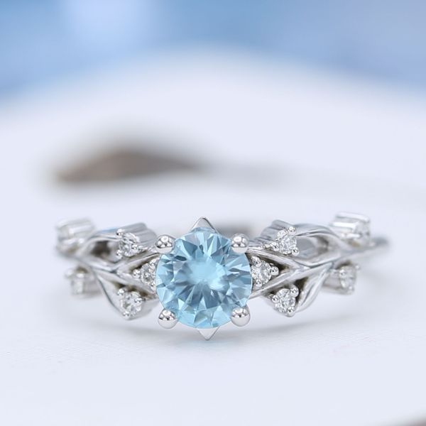Blue zircon engagement ring with antler-inspired branching band and diamond accents.