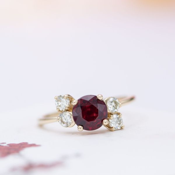 Ruby engagement ring with a cluster of heirloom diamond accents.