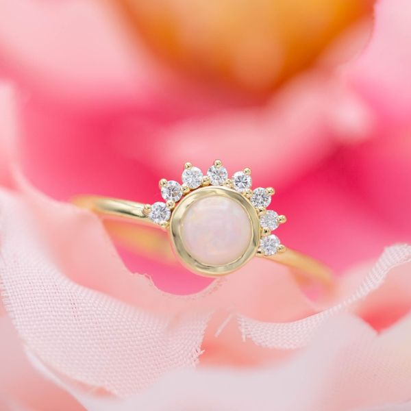A delicate, modern opal ring with an asymmetrical sunburst half-halo.