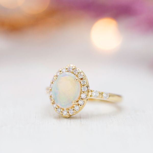 The head-on view of this engagement ring shows the classic warmth of gold, shimmering white opal, and a sparkling diamond halo.